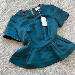 Peplum blouse. Neck and sleeves trimmed with black leather material.